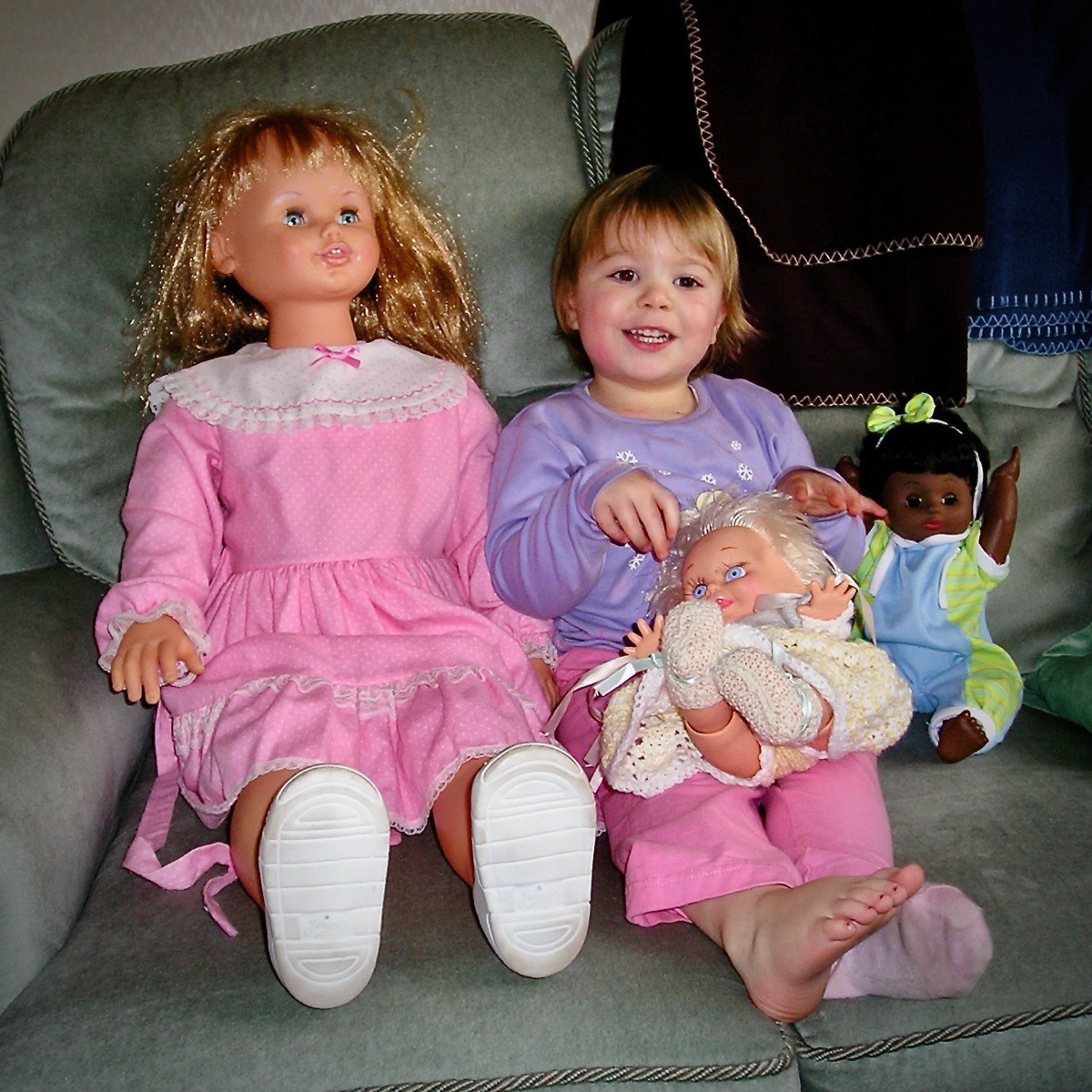 Little girl and three dolls, one bigger than her