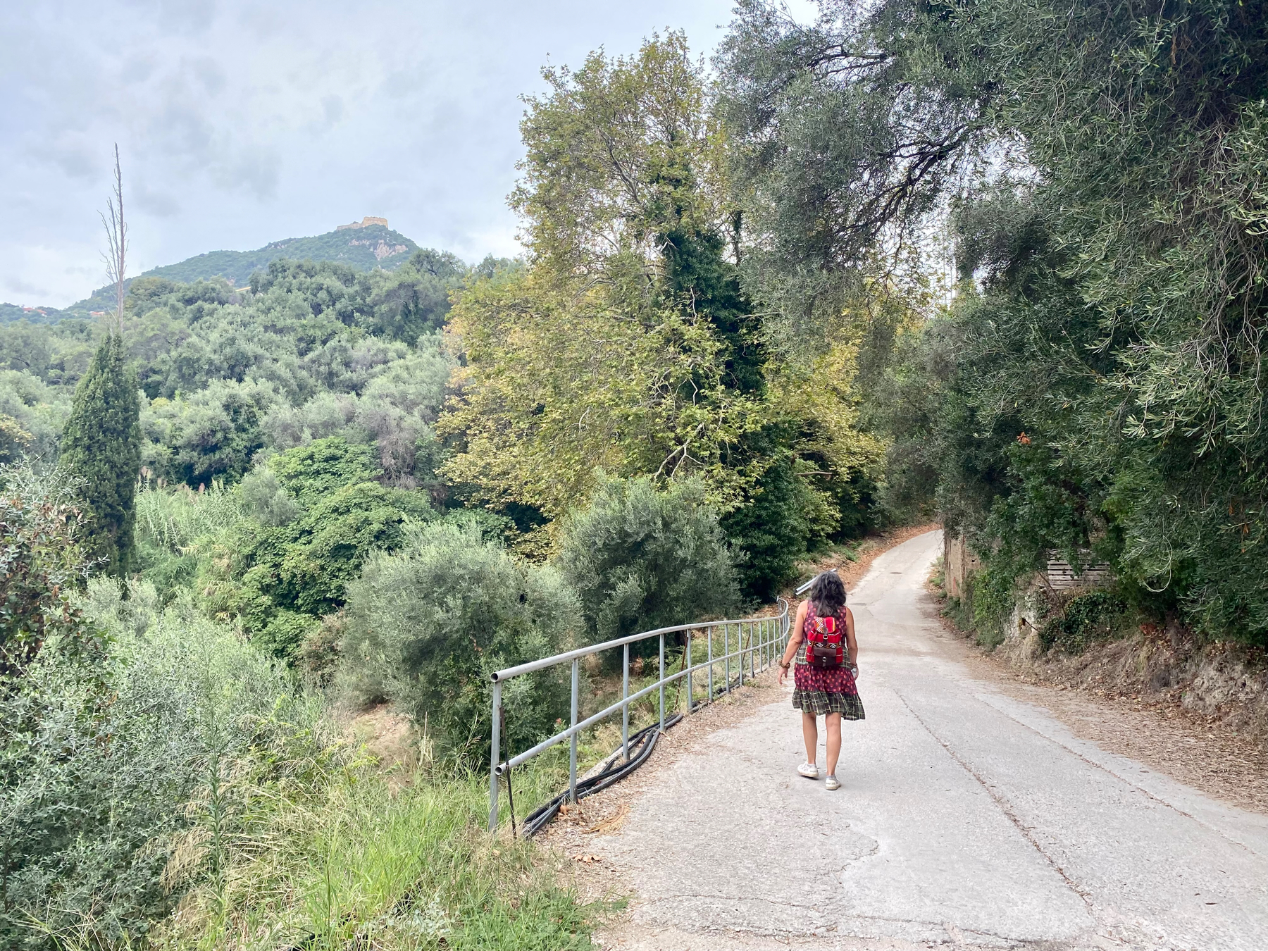 Woman walking on a narrow road on a hillside amongst trees