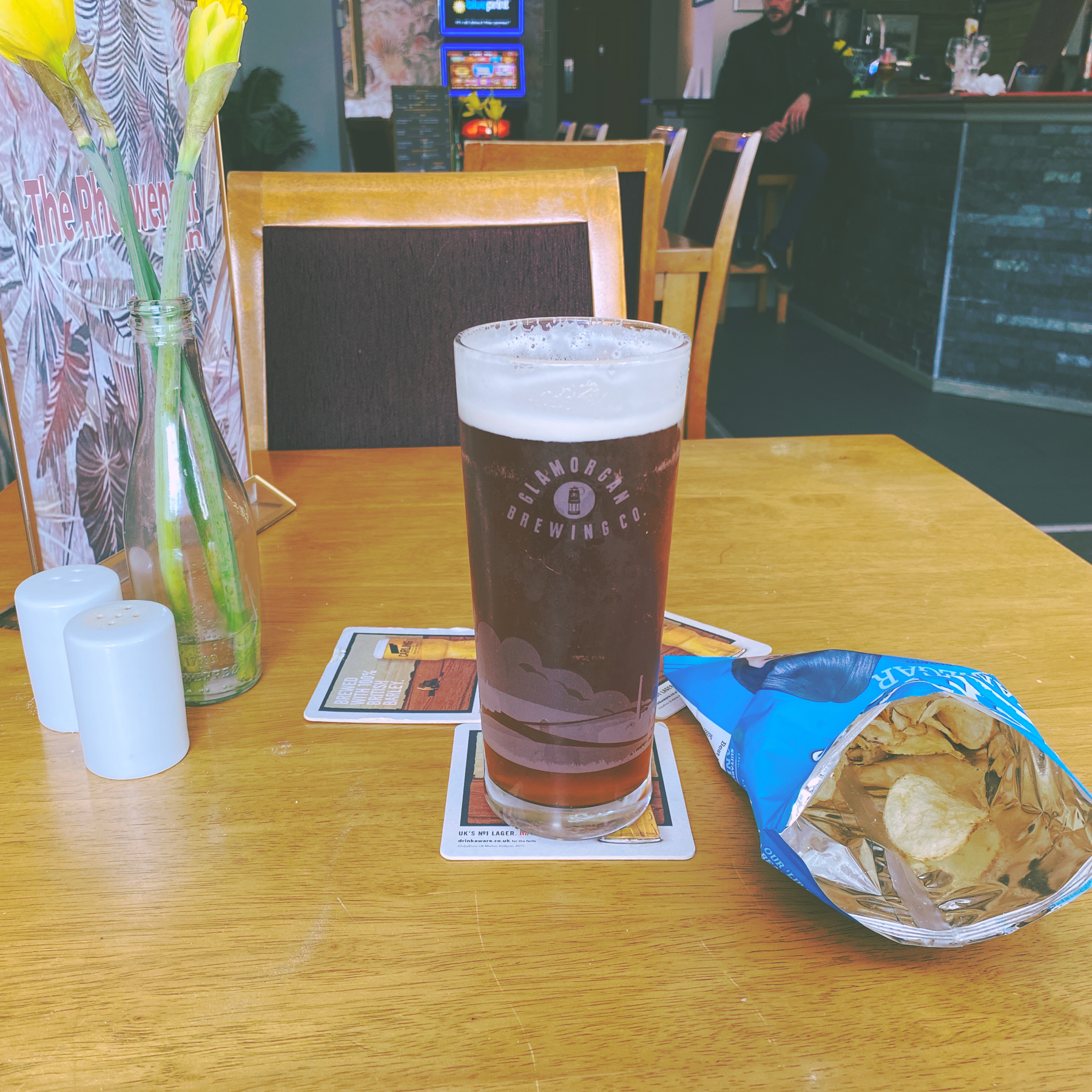 Pint of beer next to a packet of crisps