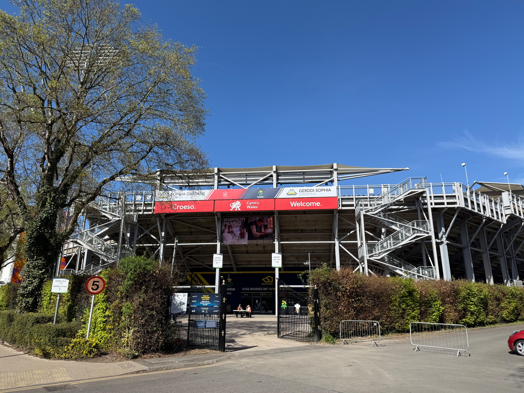 Auto-generated description: A large outdoor sports stadium with a metal structure and banners is visible under a clear blue sky.